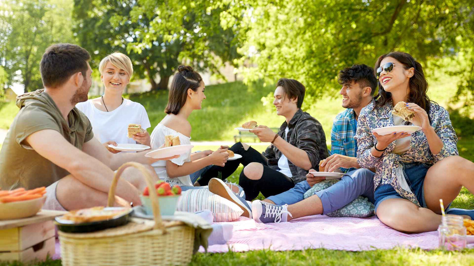 Gruppe von jungen Menschen beim picknicken mit Putensanacks im Park